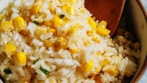 Delicious hot buttered corn rice served in a bowl with butter drizzling on top.