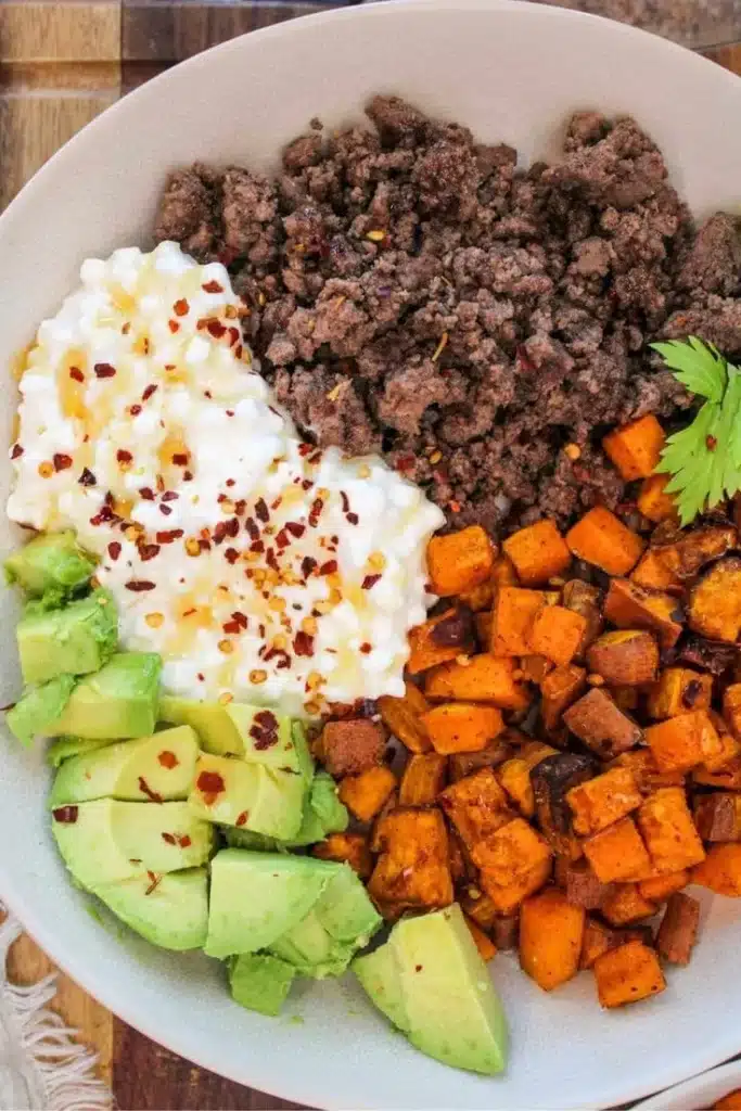 Hot Honey Sweet Potato Bowl with Ground Beef garnished with herbs.