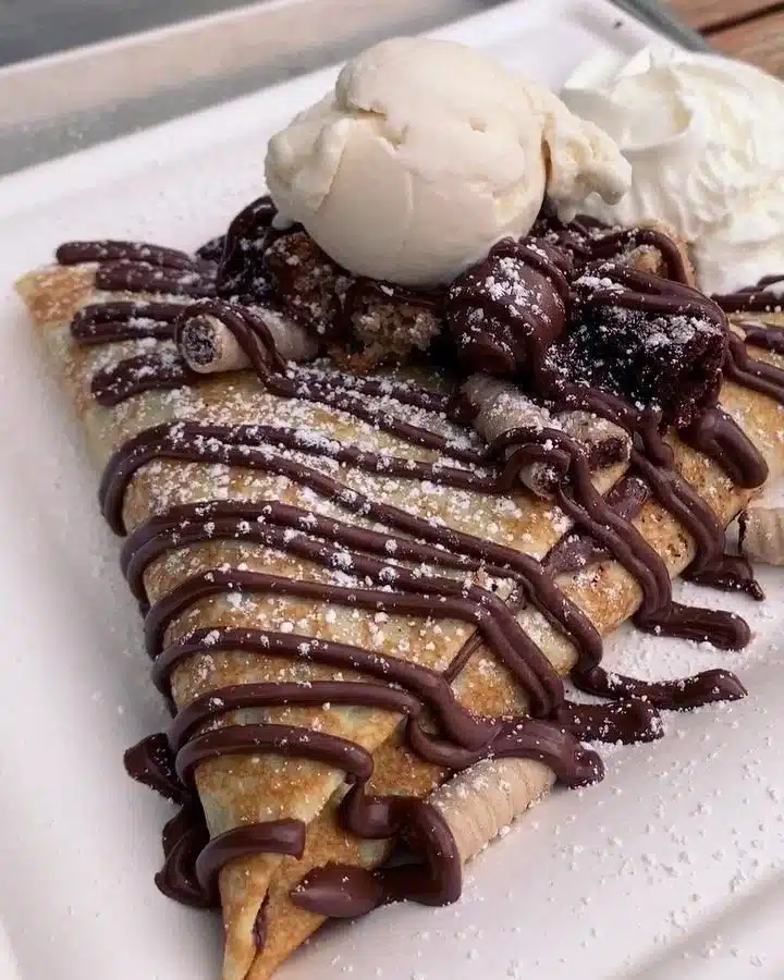 Delicious Nutella crepes topped with fresh berries on a white plate