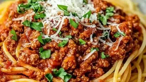 Delicious plate of Spaghetti Bolognese garnished with fresh basil and grated parmesan cheese.