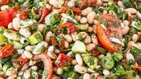 Colorful White Bean Salad with fresh vegetables and dressing in a bowl